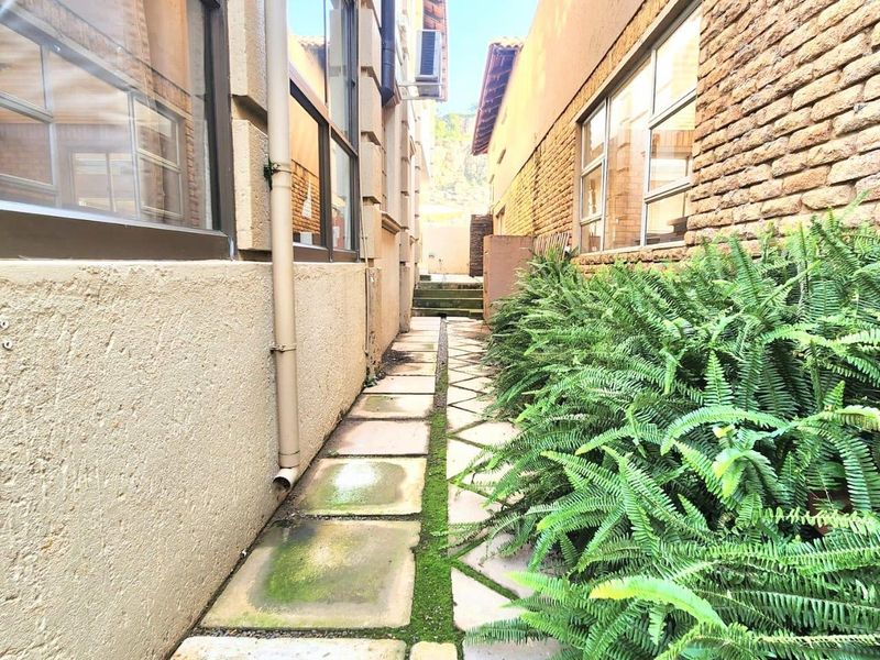 A narrow side passage between two building structures featuring paved walkways and exterior wall finishes.