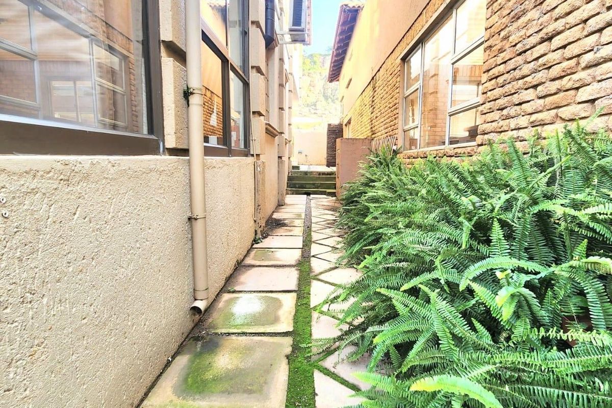 A narrow side passage between two building structures featuring paved walkways and exterior wall finishes.