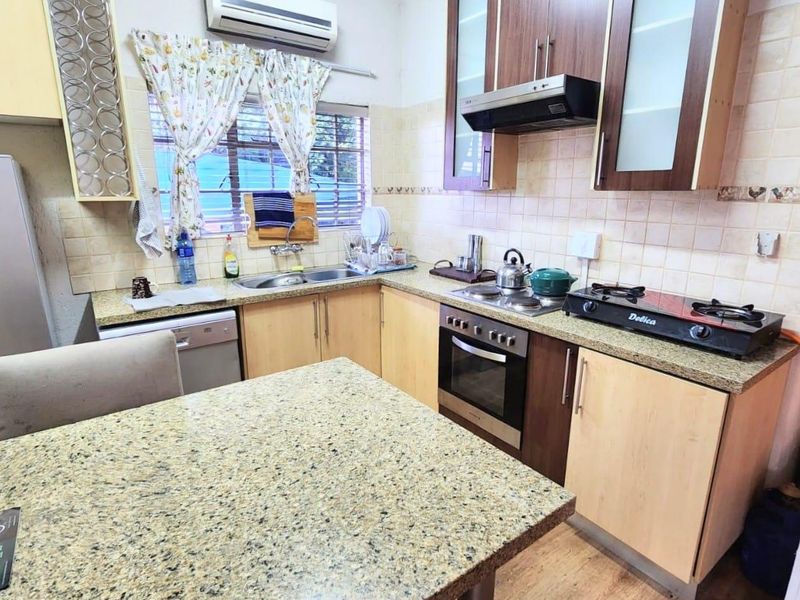 Functional kitchen featuring granite countertops, built-in oven, extractor fan, and ample cabinetry, providing a practical workspace with integrated appliances.