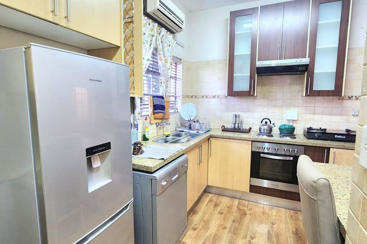 A functional kitchen featuring wood-tone cabinetry, integrated oven with extractor fan, tiled backsplash, and durable wood-look flooring.