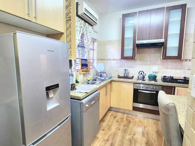 A functional kitchen featuring wood-tone cabinetry, integrated oven with extractor fan, tiled backsplash, and durable wood-look flooring.
