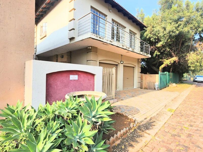 Front elevation of a two-story house featuring a double garage, a balcony with metal railings, and a paved driveway.