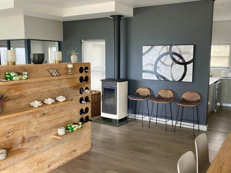 Modern open-plan living area featuring a contemporary freestanding fireplace, timber shelving partition, and light-toned laminate flooring with recessed lighting.