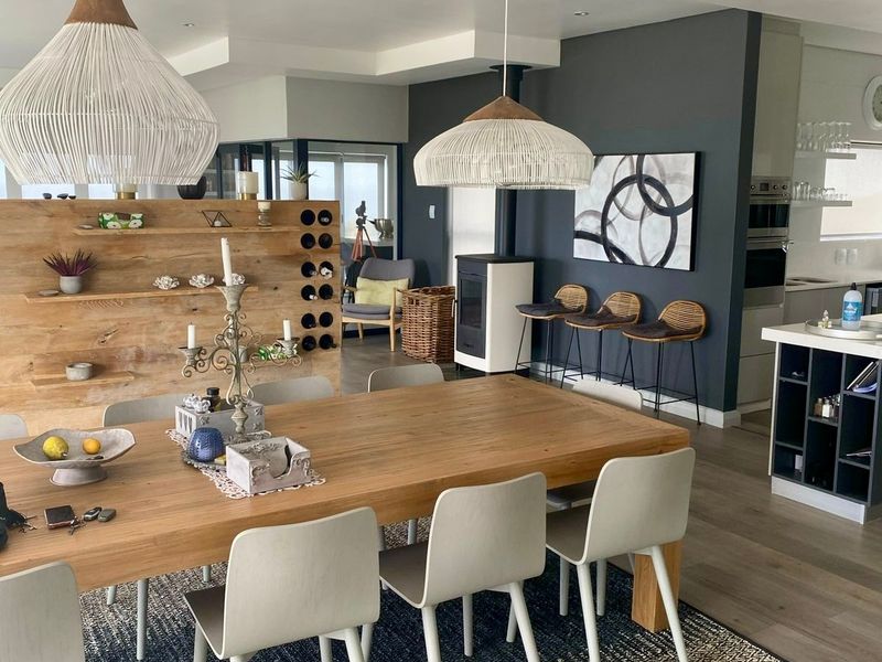 Spacious open-plan dining and kitchen area featuring modern pendant lighting, a built-in wine rack, a fireplace, and contemporary kitchen cabinetry.