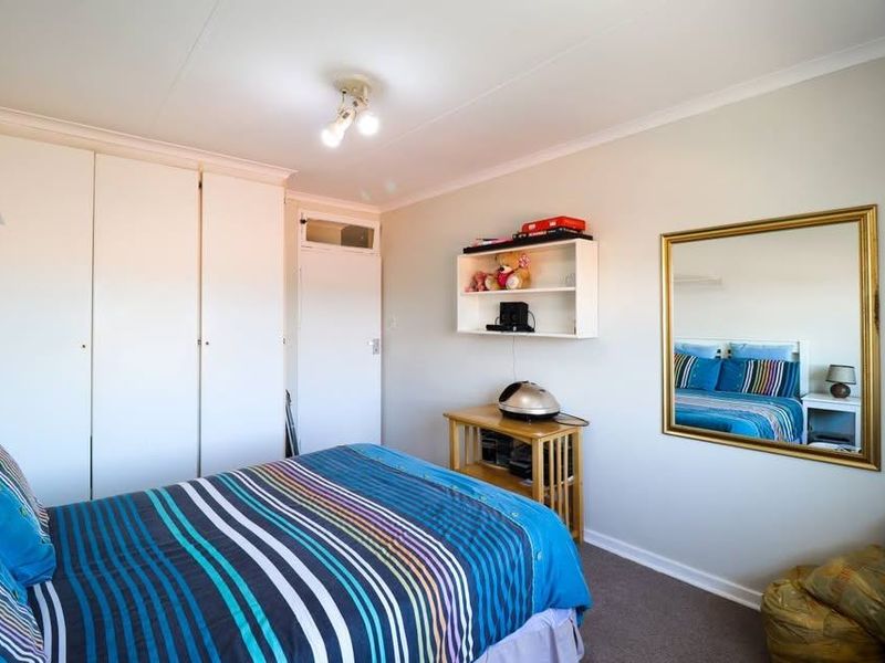 A bedroom featuring built-in cupboards, carpeted flooring, and a ceiling light fixture, offering a functional space with neutral wall finishes.