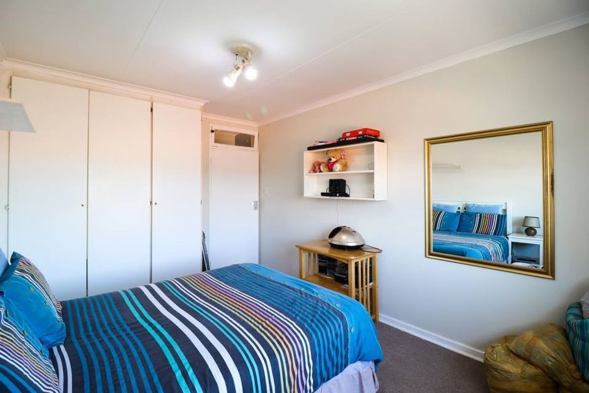 A bedroom featuring built-in cupboards, carpeted flooring, and a ceiling light fixture, offering a functional space with neutral wall finishes.
