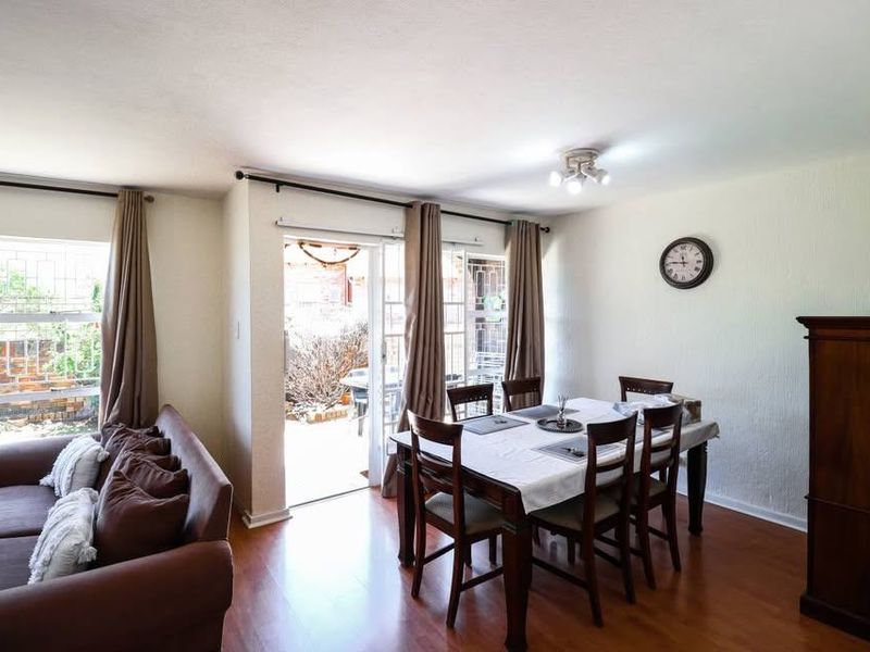 Open plan living and dining area featuring laminate flooring and direct access to an outdoor patio through a sliding glass door.