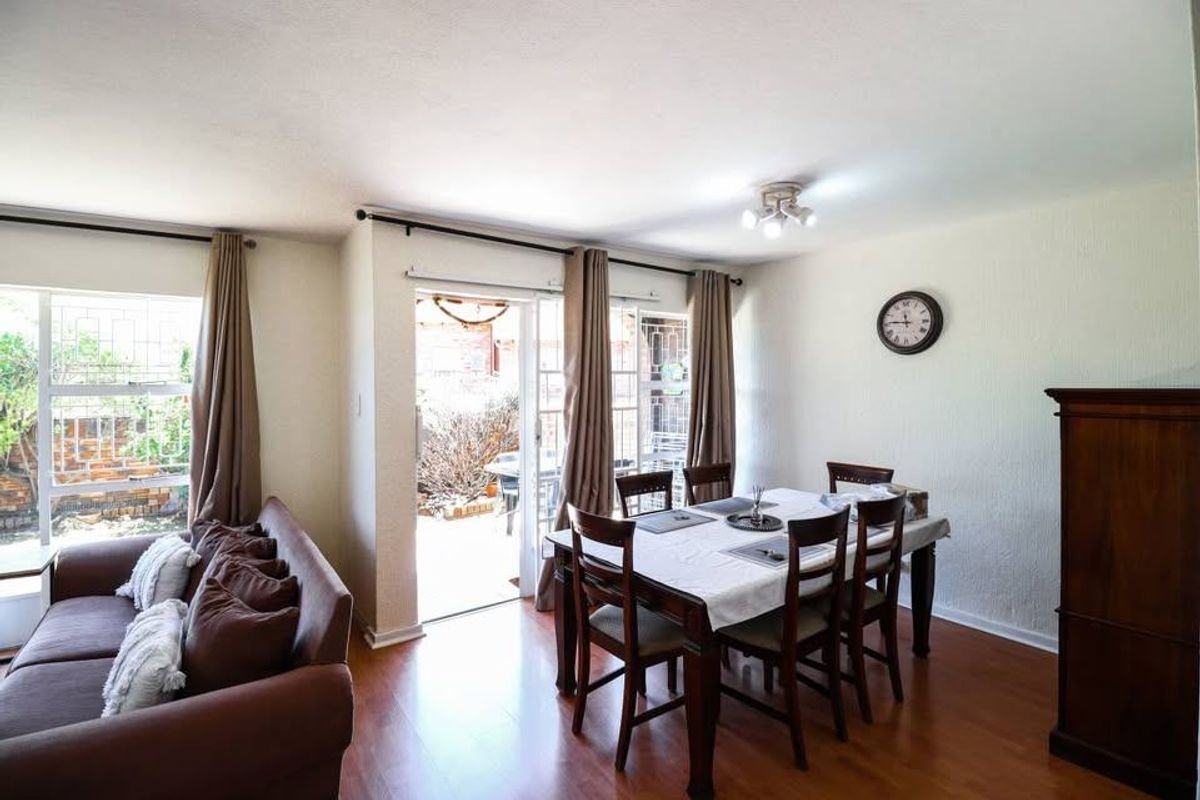 Open plan living and dining area featuring laminate flooring and direct access to an outdoor patio through a sliding glass door.