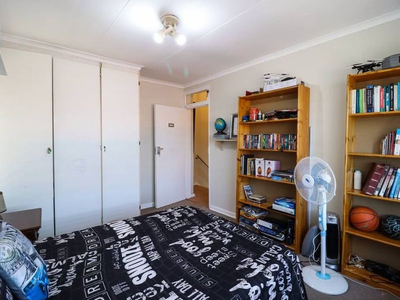 A functional bedroom featuring built-in cupboards and neutral wall finishes, providing a practical space with potential for cosmetic updates.