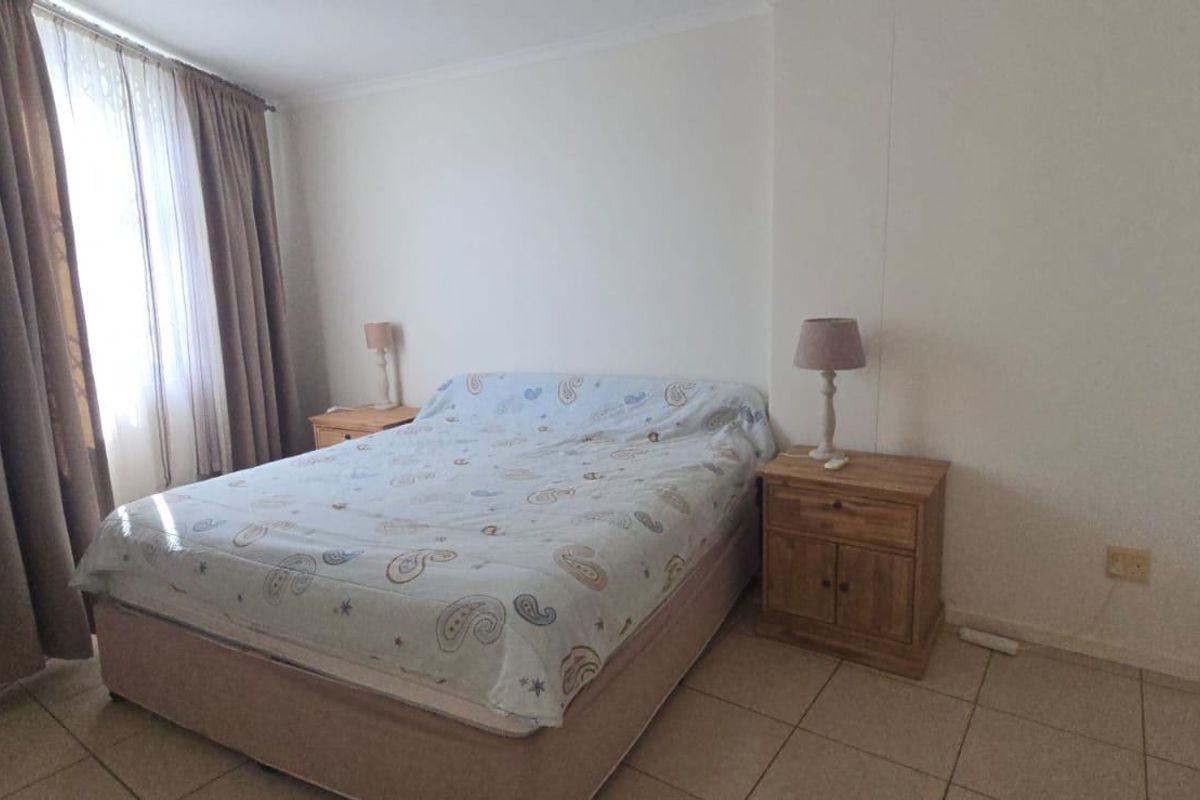 A standard bedroom featuring tiled flooring and neutral wall finishes, providing a functional and well-lit sleeping space.