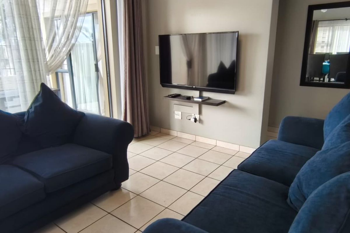 A living room featuring tiled flooring and a large sliding glass door providing access to an outdoor area.