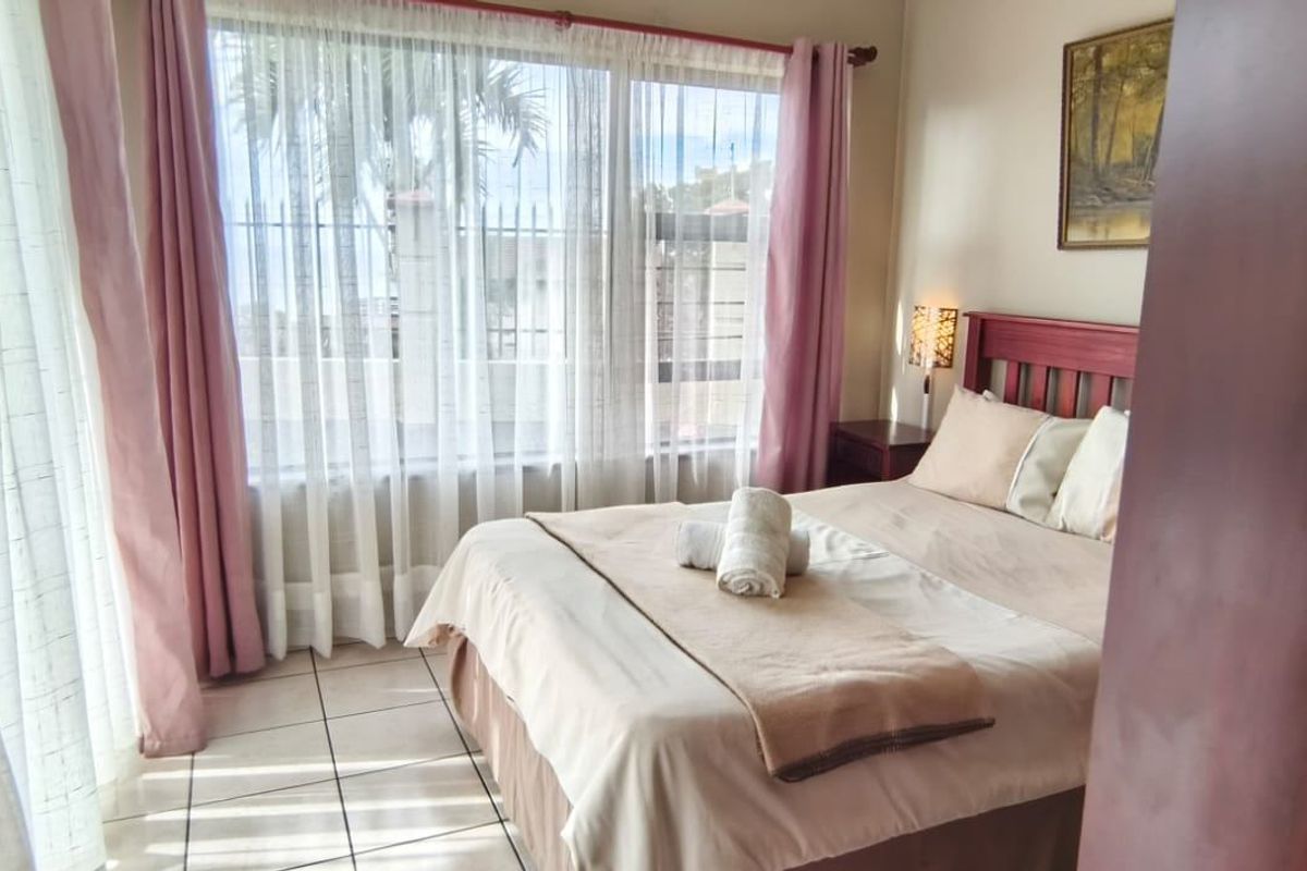 A bedroom featuring tiled flooring and a large window that allows for natural light.
