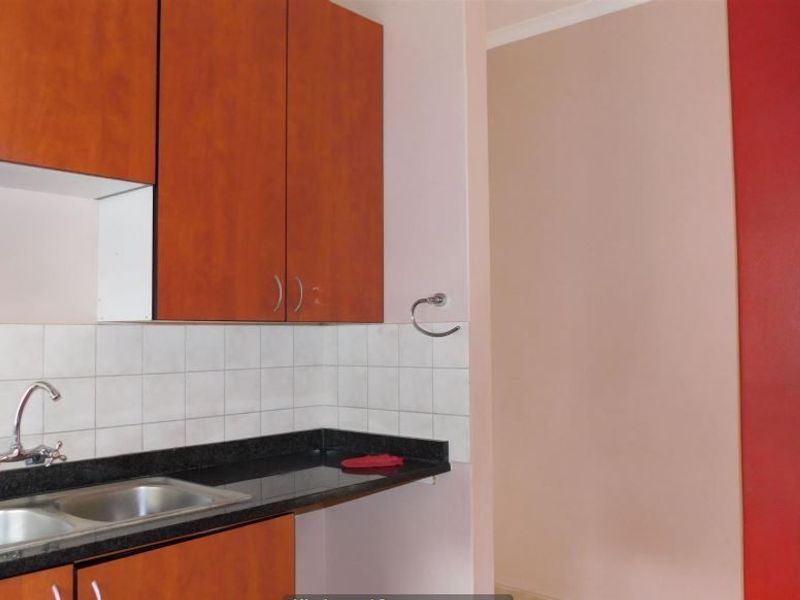 A functional kitchen area featuring laminate cabinetry, granite countertops, a double bowl stainless steel sink, and a tiled backsplash.