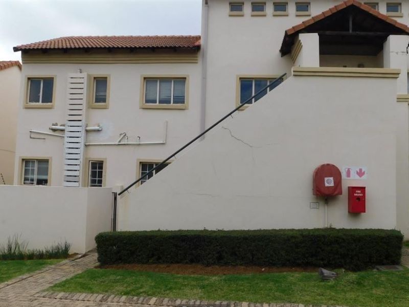 Exterior view of an apartment building facade featuring a tiled roof, paved walkways, and installed fire safety equipment.