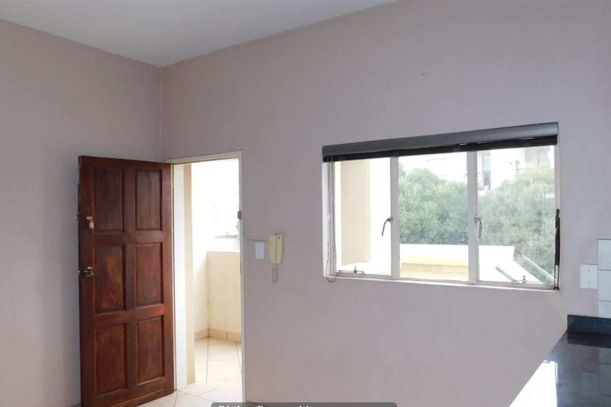 A functional kitchen area featuring granite countertops, a tiled backsplash, and a doorway leading to an adjacent balcony space.