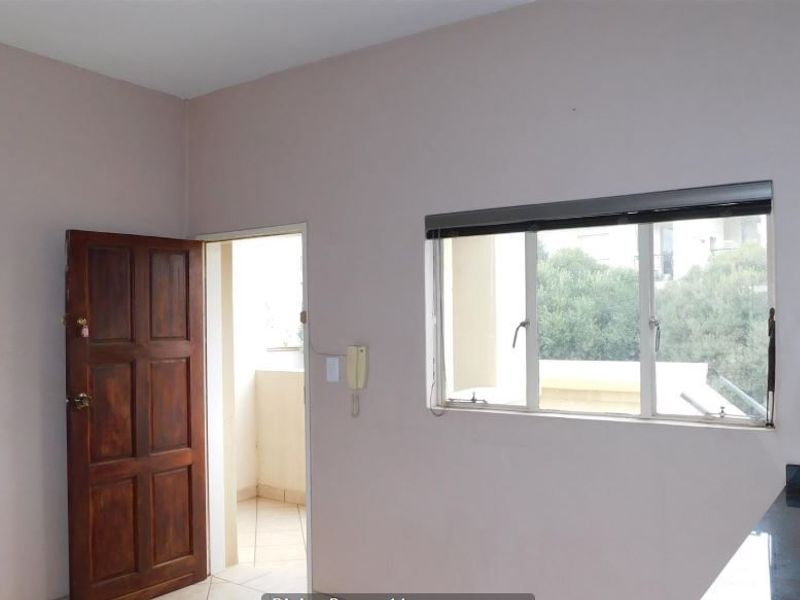 A functional kitchen area featuring granite countertops, a tiled backsplash, and a doorway leading to an adjacent balcony space.