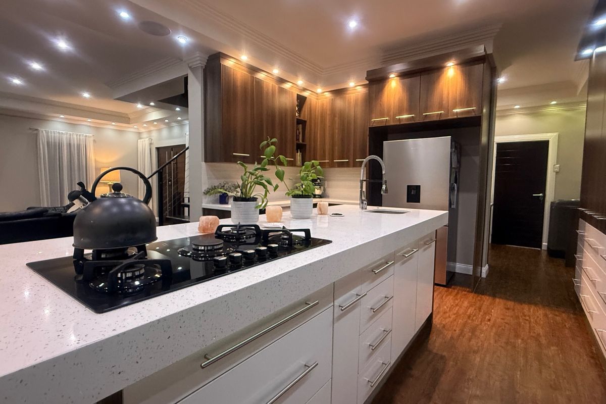 Modern kitchen featuring a large stone island benchtop with integrated gas cooktop, sleek cabinetry, and high-quality finishes throughout.