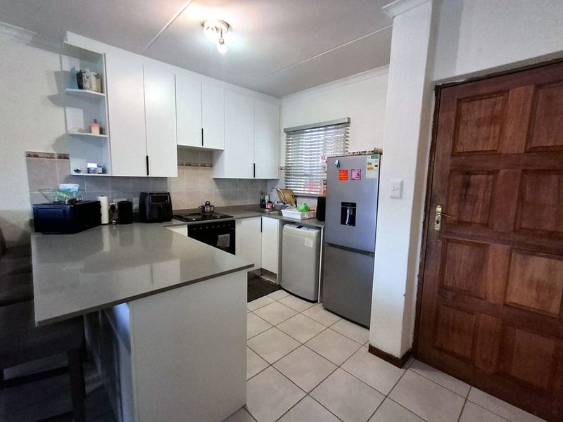 A functional kitchen featuring white cabinetry, stone countertops, tiled flooring, and a tiled backsplash, providing a clean and practical workspace.