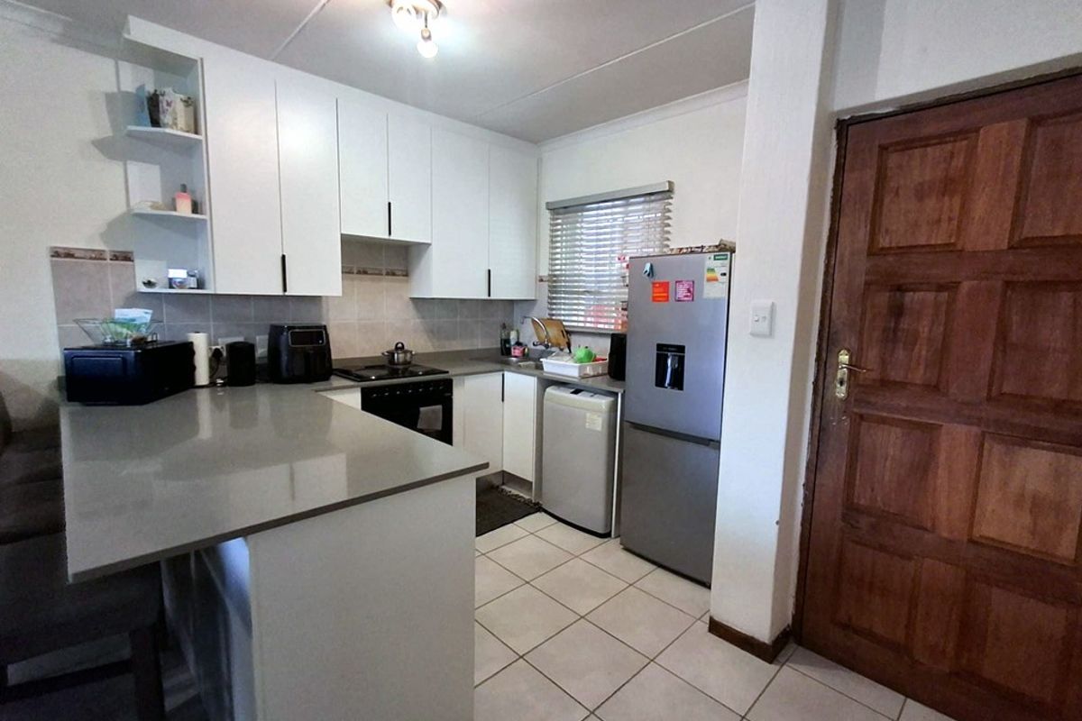 A functional kitchen featuring white cabinetry, stone countertops, tiled flooring, and a tiled backsplash, providing a clean and practical workspace.