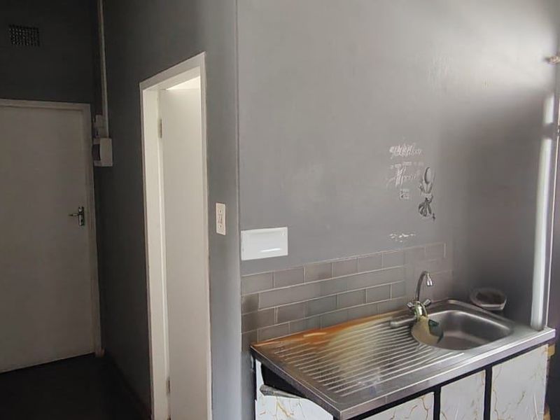 A compact kitchen area featuring a stainless steel sink, subway tile backsplash, and built-in cabinetry, providing a functional space for food preparation.