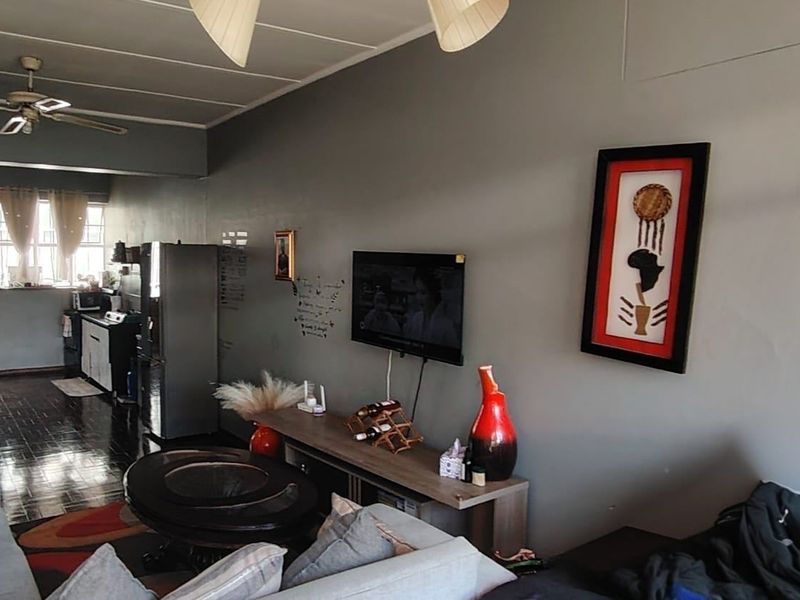 An open-plan living area featuring tiled flooring and a ceiling fan, seamlessly connecting the lounge space to the kitchen area.