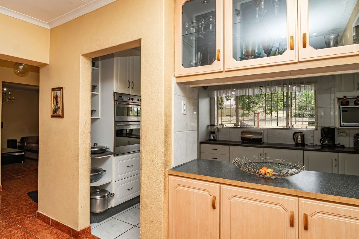 A functional kitchen featuring wood-finish cabinetry, a double wall oven, and a dedicated scullery area with additional storage and workspace.