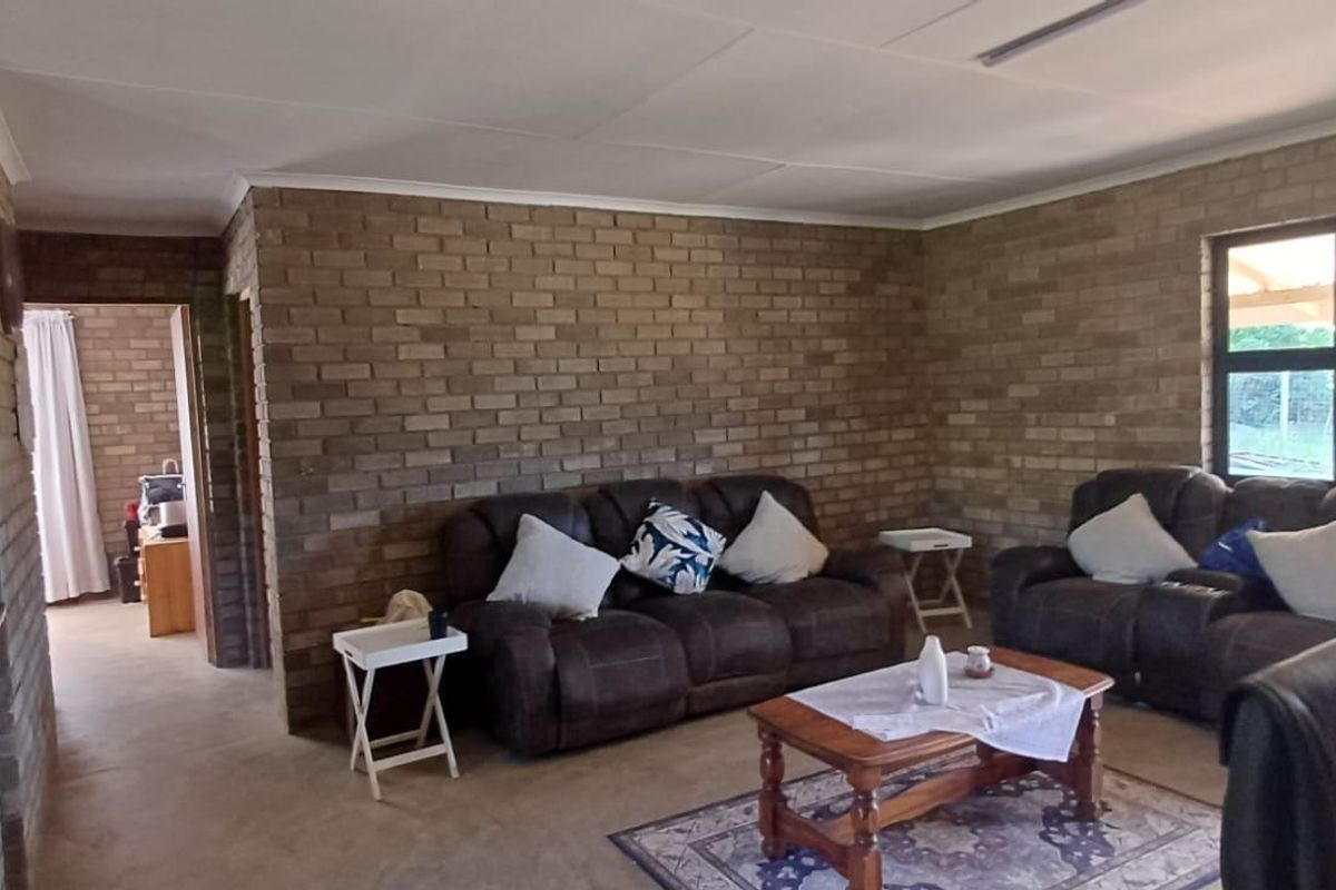A living room featuring exposed brick walls, tiled flooring, and natural light through an aluminium-framed window.
