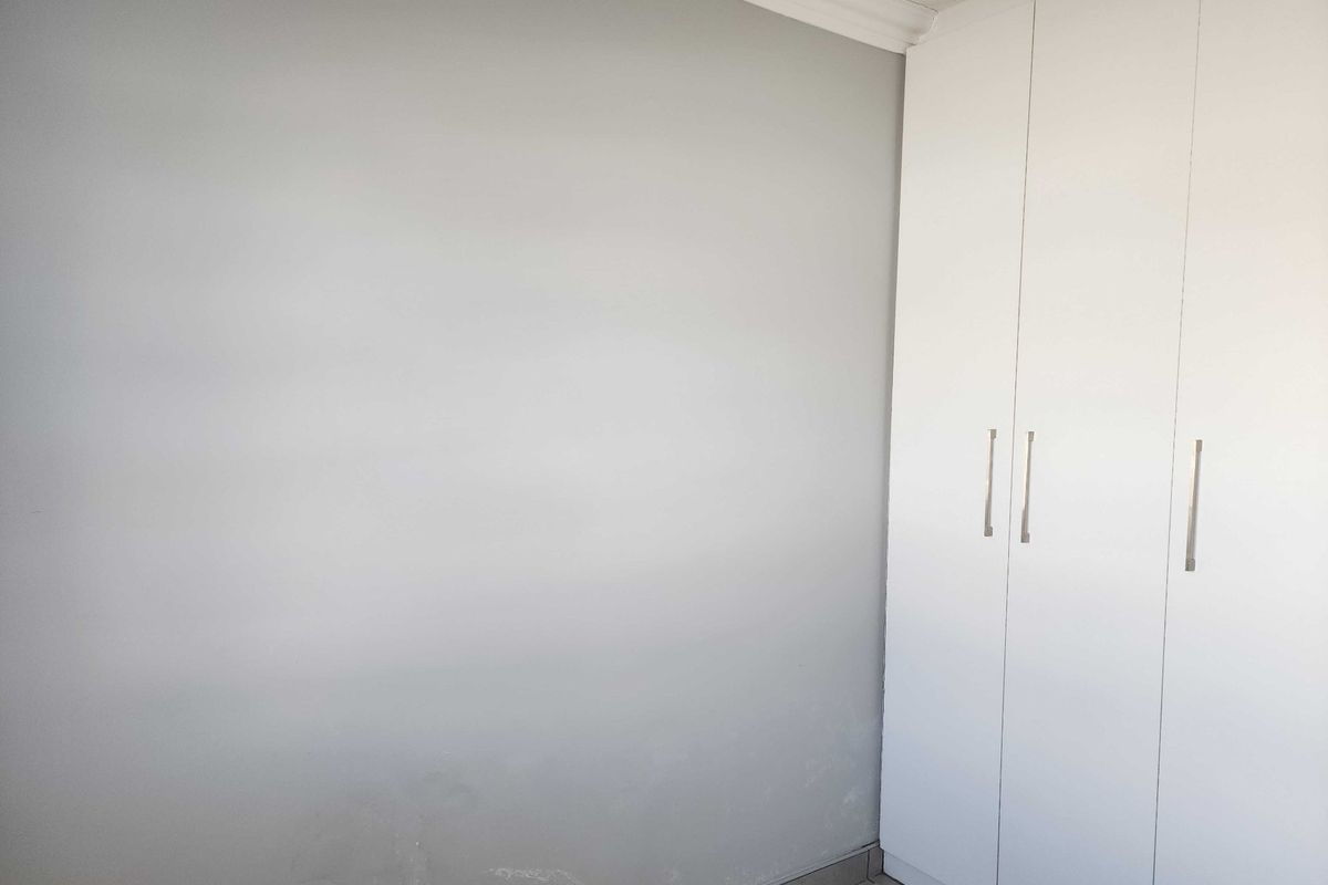 A clean, empty bedroom featuring white built-in cupboards and neutral wall finishes, providing a blank canvas for personalization.