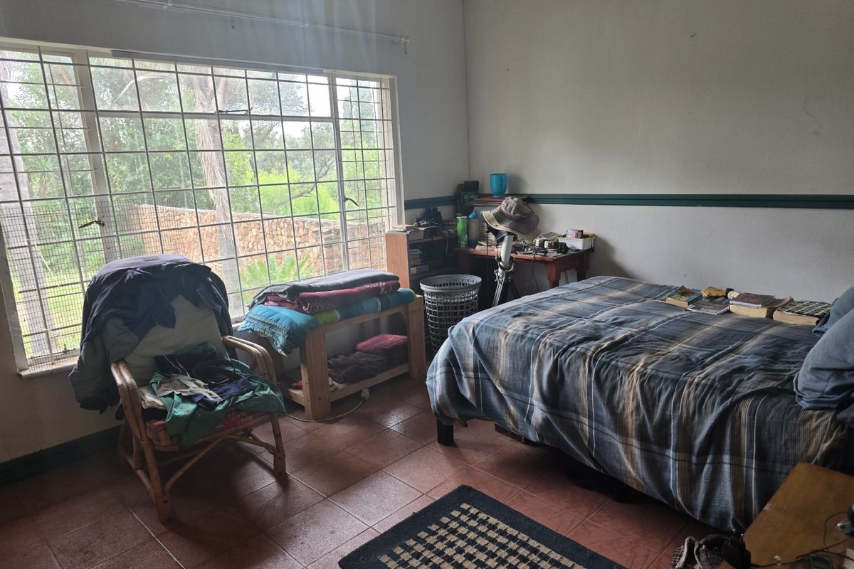 A bedroom featuring tiled flooring, a large window with security bars, and an installed air conditioning unit.