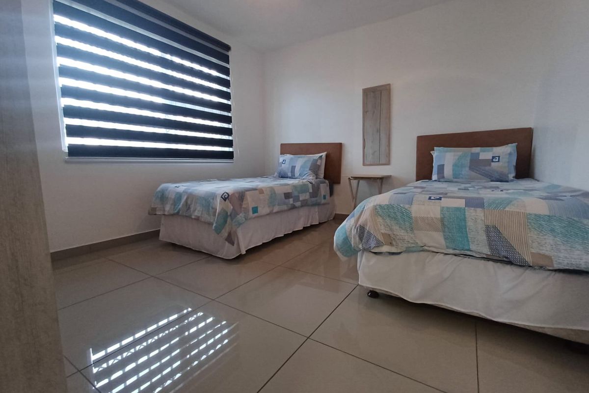 A well-maintained bedroom featuring large format floor tiles and modern zebra blinds, providing a clean and neutral space.