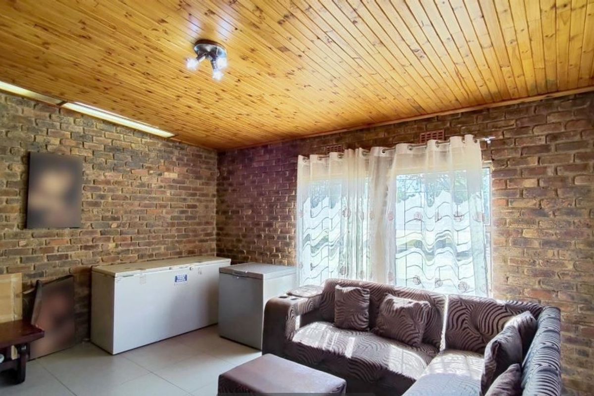 Living room featuring exposed brick walls, a warm timber tongue and groove ceiling, and tiled flooring, offering a rustic aesthetic.