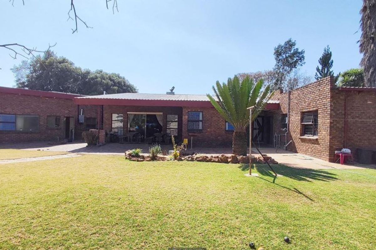 Rear view of a face brick house featuring a covered patio area and a spacious garden with established lawn.