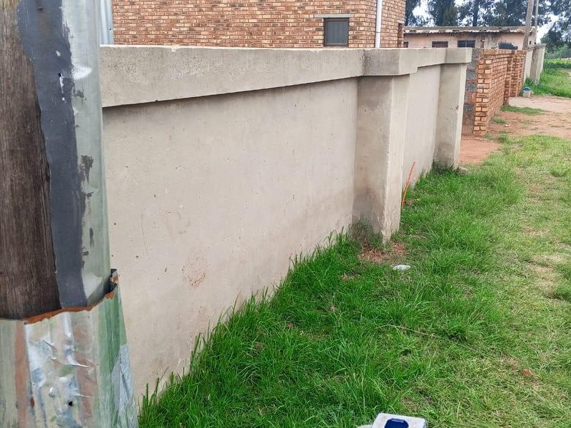 View of the property's exterior boundary wall and brick facade, showing the street-facing perimeter and utility infrastructure.