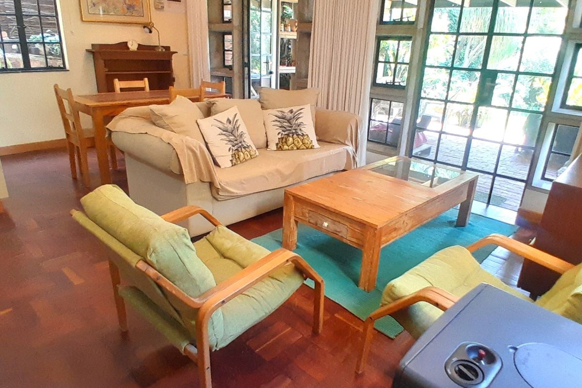 A living room featuring parquet flooring and large steel-framed glass doors providing access to the outdoor area.