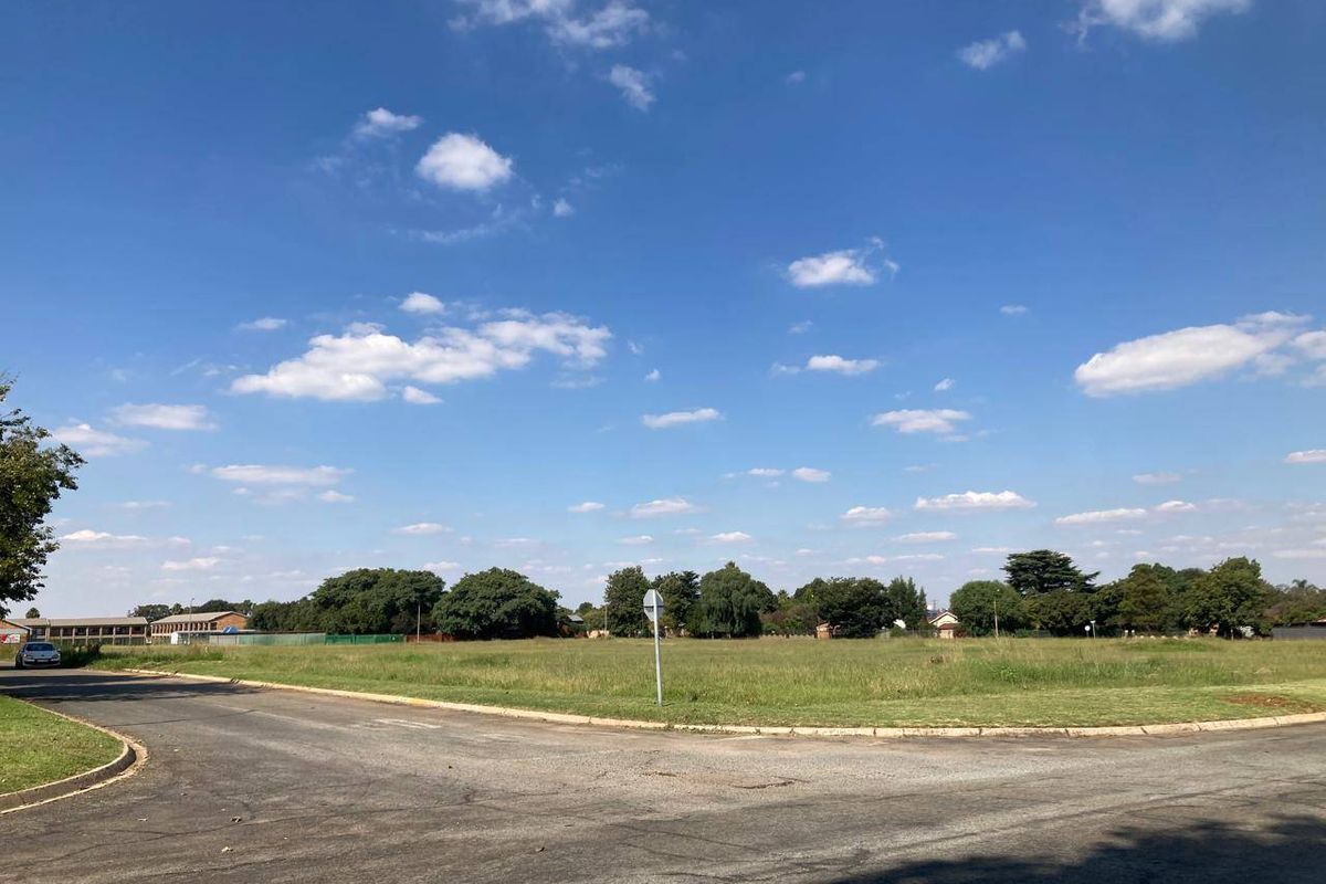 A view of a vacant residential plot situated on a corner lot with paved road access.