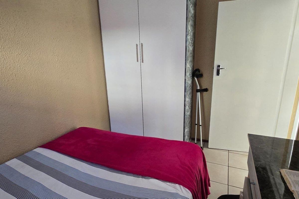 A bedroom featuring tiled flooring and a built-in wardrobe, providing functional storage space within the apartment.