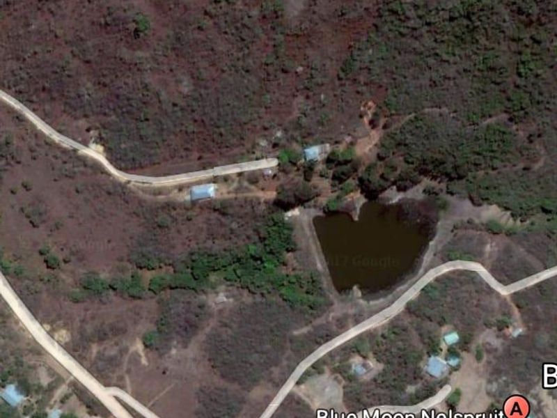 Aerial satellite view of the farm property showing access roads, natural landscape, and a small dam on the site.