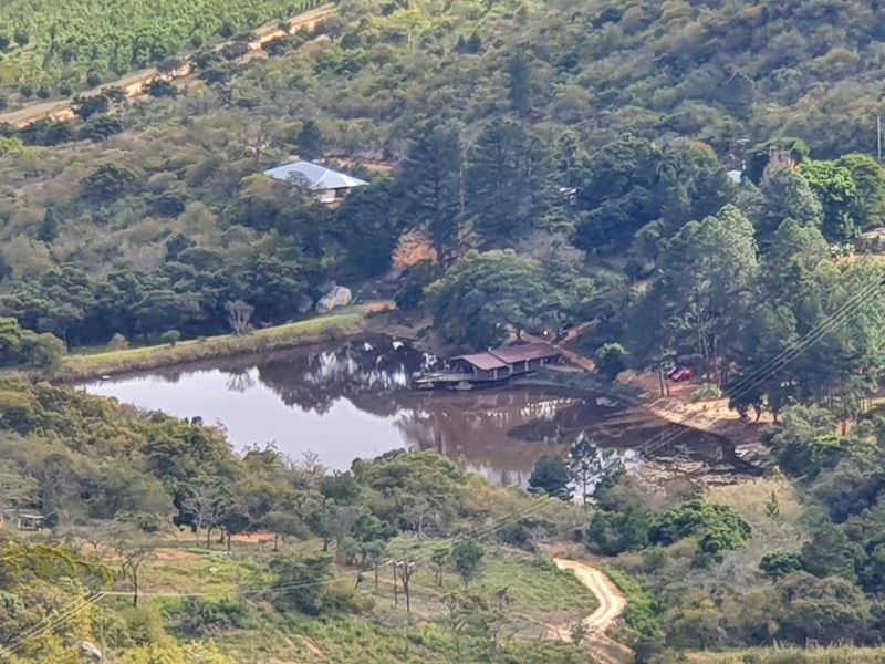 An aerial view of a rural farm property featuring a large dam, surrounding woodland, and access via a dirt road.