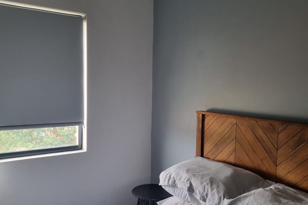 A well-maintained bedroom featuring a split-system air conditioner and a modern roller blind, providing a comfortable and functional living space.
