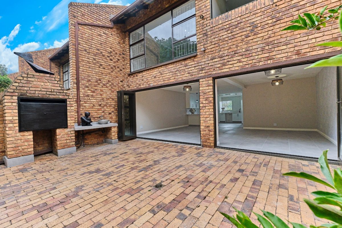 Rear patio area featuring brick paving, a built-in braai, and large folding doors providing seamless access to the interior living space.