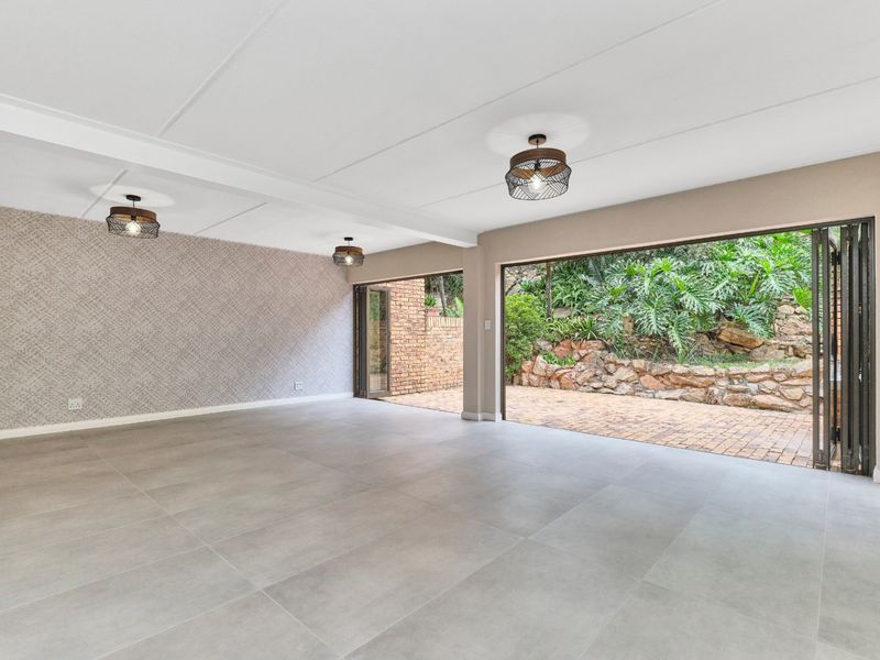 Spacious, light-filled living area featuring large bi-fold doors that open onto a private paved patio and garden area.
