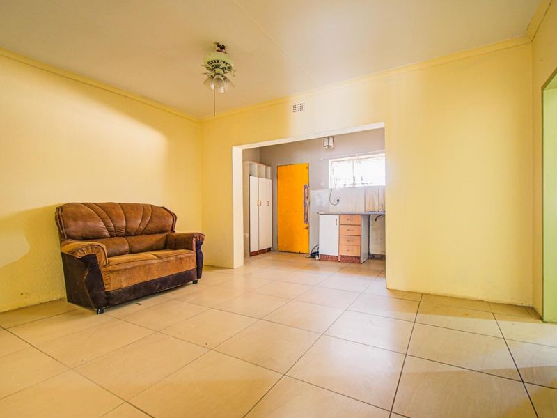 Open-plan living area featuring tiled flooring and a connected kitchen space with built-in cabinetry and sink.