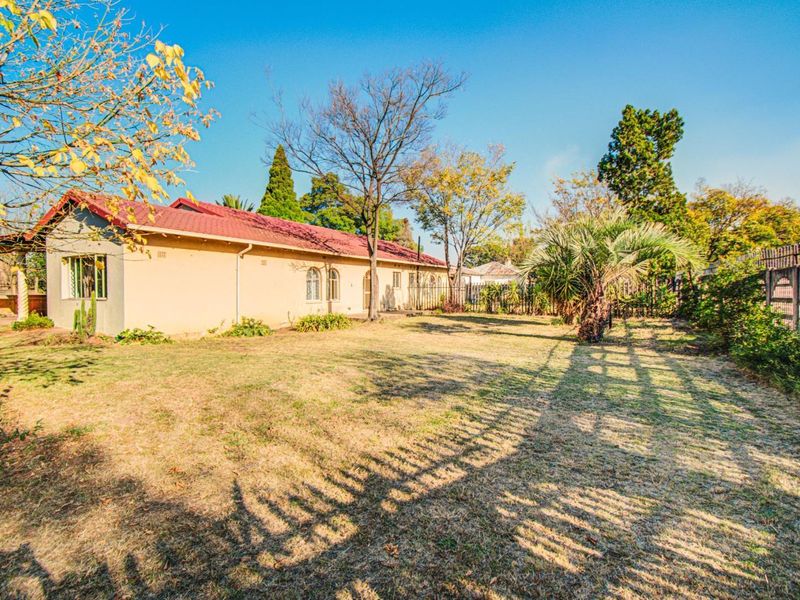 A view of the rear exterior of the house featuring a tiled roof, plastered walls, and a spacious garden area with perimeter fencing.