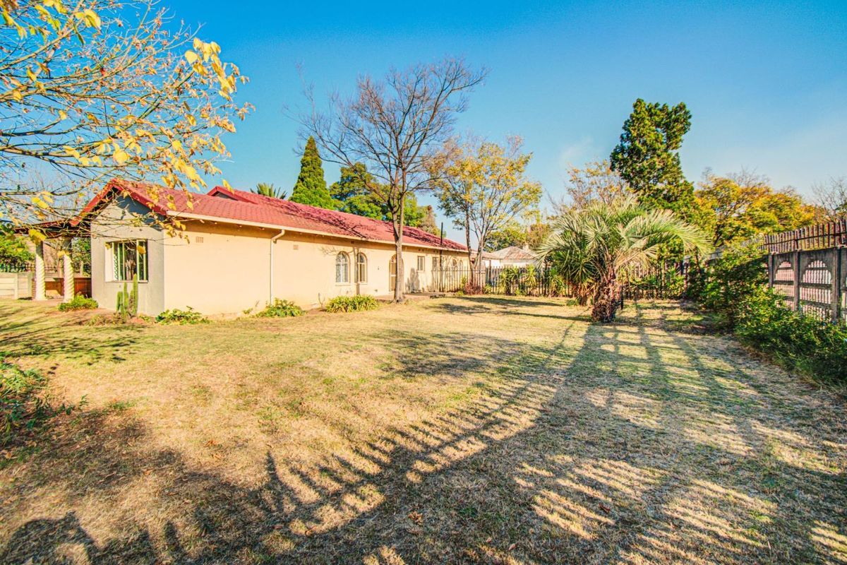 A view of the rear exterior of the house featuring a tiled roof, plastered walls, and a spacious garden area with perimeter fencing.