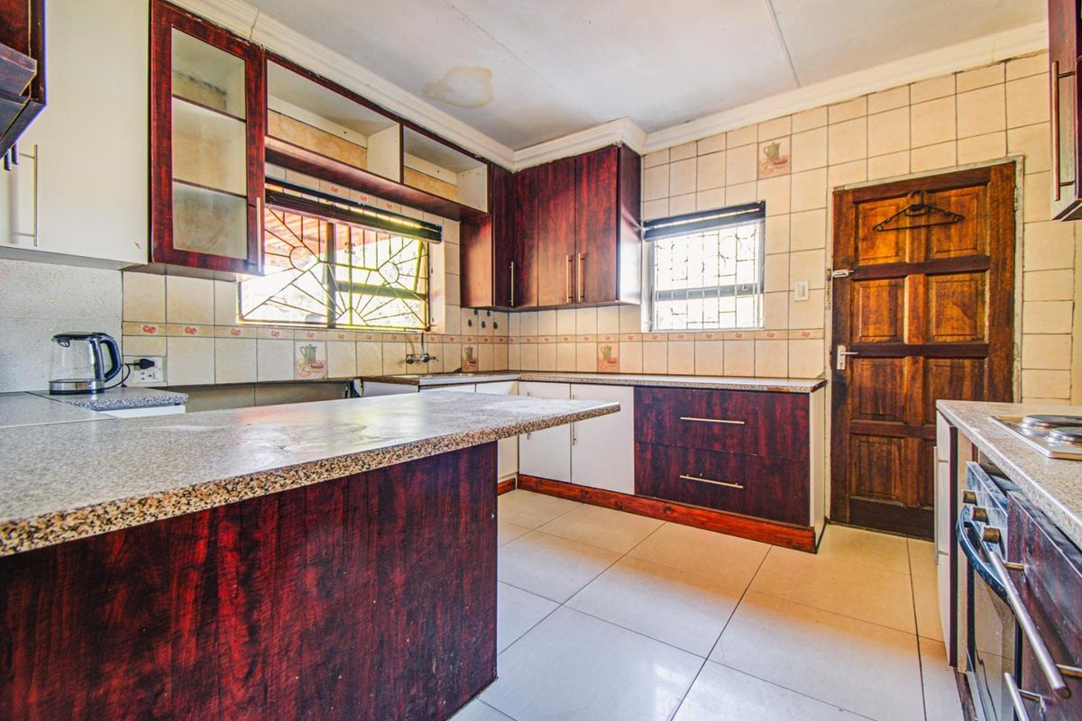 A dated kitchen featuring laminate cabinetry, granite-look countertops, and ceramic tiling, requiring cosmetic updates to modernize the space.