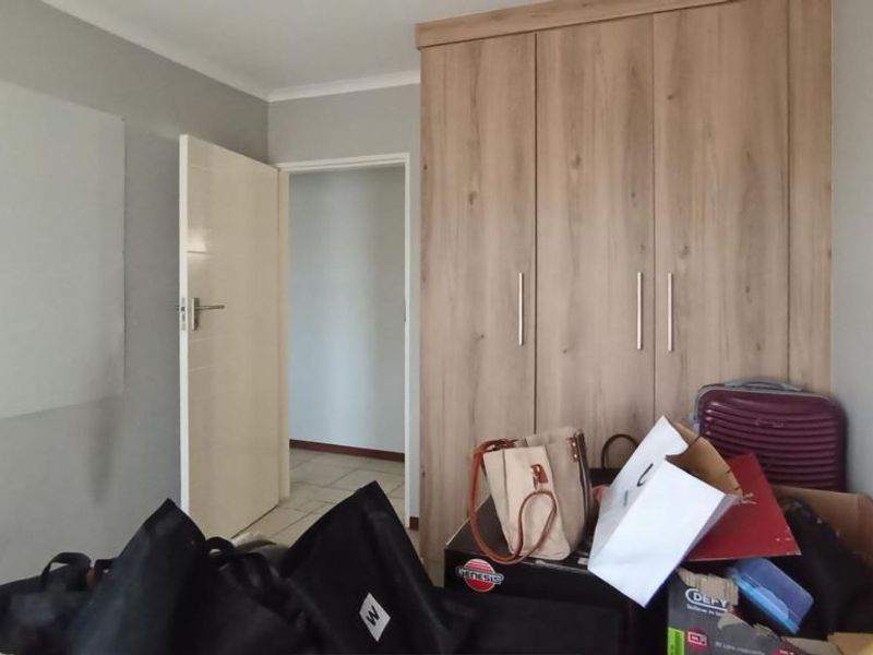 A bedroom featuring a modern wood-finish built-in wardrobe and neutral wall tones, providing a functional storage solution within the apartment.