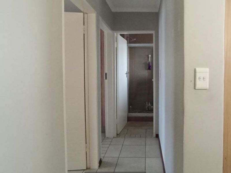 A functional hallway with tiled flooring providing access to internal rooms and a bathroom with a shower enclosure.