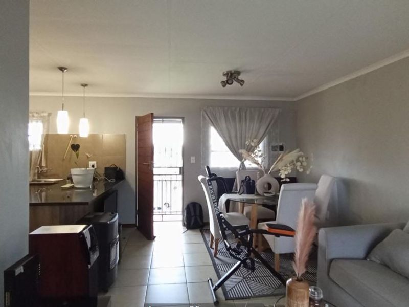 Open-plan living and dining area featuring tiled flooring, granite kitchen countertops, and direct access to an exterior security gate.