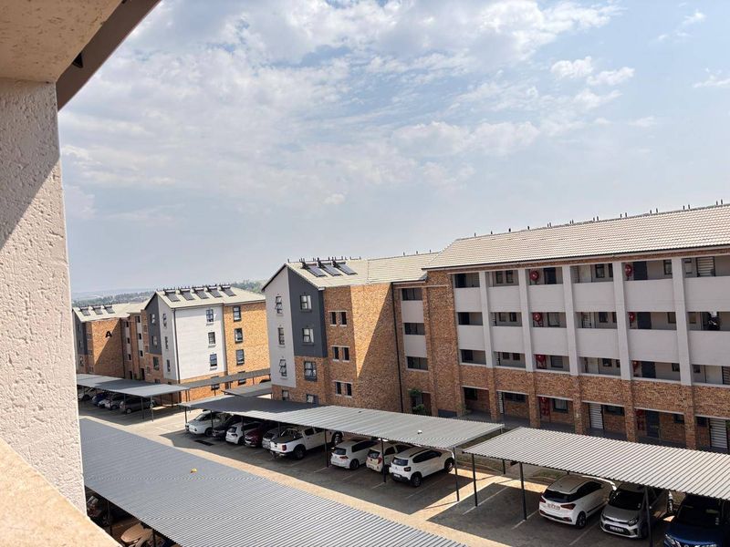 Elevated view overlooking the apartment complex grounds, featuring multiple residential blocks and covered parking bays for residents.