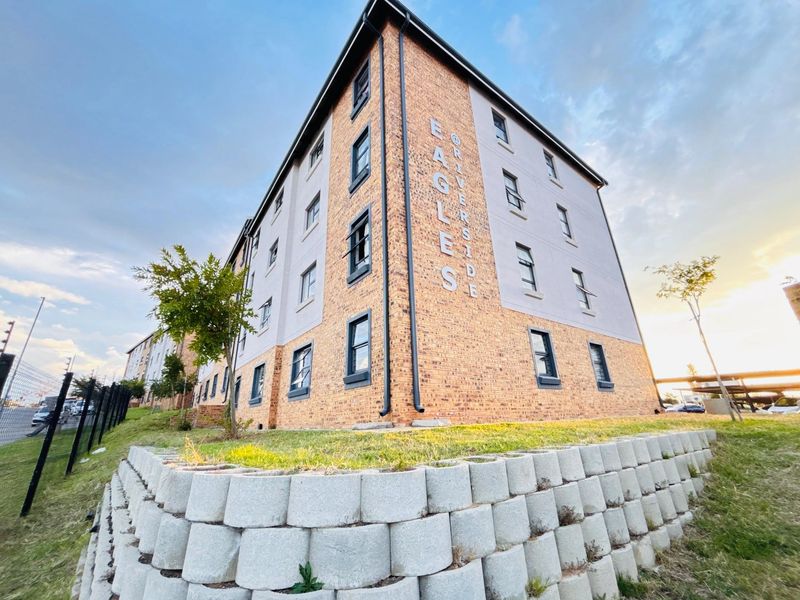 Exterior view of the apartment building featuring a brick and rendered facade with landscaped retaining walls and secure perimeter fencing.